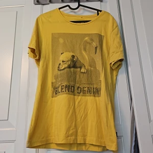 Gul T-shirt  - Gul T-shirt med en Bulldog som ligger i en uppblåsbar Flamingo med texten Blend Denim.