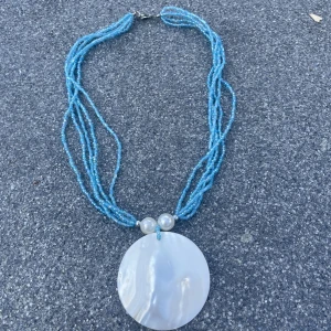 Fint halsband - Fint blått pärlhalsband. Den stora berlocken är i snäckskal material. Väldigt fint skick
