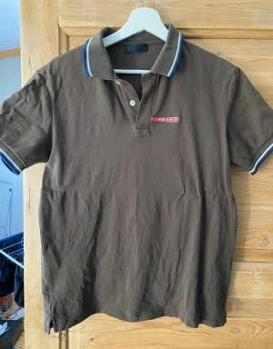 Prada polo - Brun/olive färg, bra kondition authentic. Sitter mer som en M (Sido taggar finns ej kvar) 