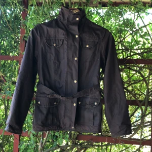 Oljerock jacka - Äkta oljerock, oanvänd. Dragkedja, plus knappar, 4 fickor utvändigt framsida, 1 innerficka. Stl 12, känns som small/ liten medium.