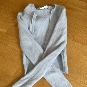 Ljusblå kort kofta med luva. - Jättefin kort ljusblå kofta med luva. Koftan är endast använd en gång och är i nyskick!