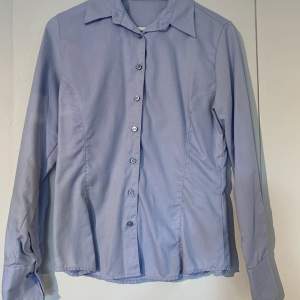 Ljusblå skjorta från Bosweel stl 38, skulle säga att den är mer stl 36. Liten fläck som inte gått bort i vanlig tvätt men ej provat med fläckborttagningsmedel.