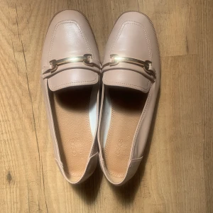svart blus, rosa loafers, svarta loafers med kedja  - Rosa platta loafers med kant och bred passform storlek 37. Oanvänd. 150:- Svarta loafers med kedja storlek 37. Oanvänd. 200:- Svart blus med långa ärmar och v-ringning av satin storlek 34. Oanvänd. 150:-