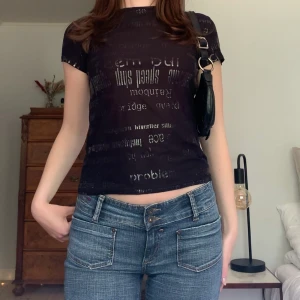 Mönstrad babytee - Svart babytee med ett mönster av glansiga bokstäver, från märket Randigarutan! 🌟