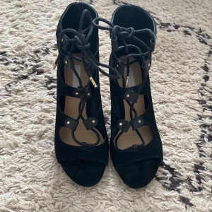 Heels i mocka/suede - Svarta mockaheels från HM. Snörning. Klackhöjd ca. 8 cm. Storlek 36. Använda vid ett (1) tillfälle. 