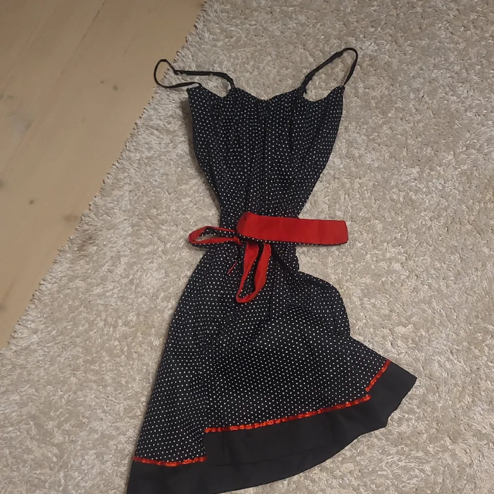 En svart klänning med vita prickar och röda detaljer, kommer inte till användning. Har bara använt 2 gånger. Snygg till sommaren🩶. Klänningar.