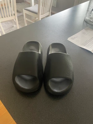 Yeezy slides -  Ett par otroligt sköna onyx yeezy slides säljs pga strlk. Använda några gånger men inga fel skick 8/10. Ny pris 2699kr pris diskuterbart, STORLEK 42