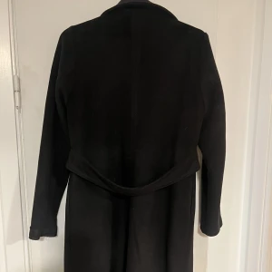 Kappa medellång svart - Väldigt fin kappa från NA-KD.  Band i bak på kappan. Använd ett fåtal gånger.