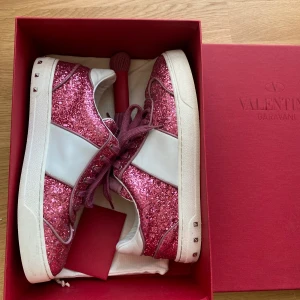 VALENTINO GLITTER TRAINERS - Säljer ett par rosa Valentino Gravani Rockstud Glitter Trainers i storlek 38. Mycket bra skick, se sista bild för defekt då en utav nitarna saknas. Originalförpackning, dust bag och extra skosnören medföljer. Kanske de coolaste skorna någonsin ❤️