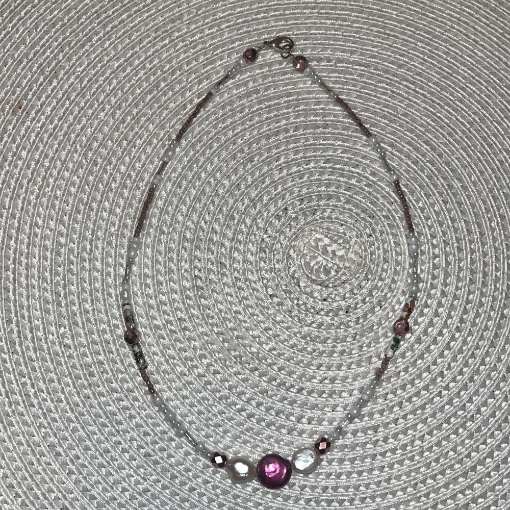 Ett pärl halsband som är lila och vit. Accessoarer.