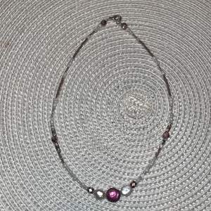 Ett pärl halsband som är lila och vit