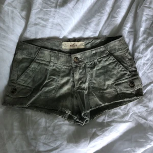 Gröna lågmidjade shorts  - Flammigt gröna lågmidjade shorts från Hollister med små fickor som försluts med knappar. Storleken är w24. Dessa är så coola och snygga, önskar att de fortfarande passade mig.