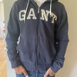 Säljer nu en väldigt snygg hoodie från märket Gant. Blir perfekt till sena sommarkvällar och mot hösten. Den är i storlek Large. Den är i bra skick utan defekter. Personen på bilden är 186cm. Hör av er vid funderingar!