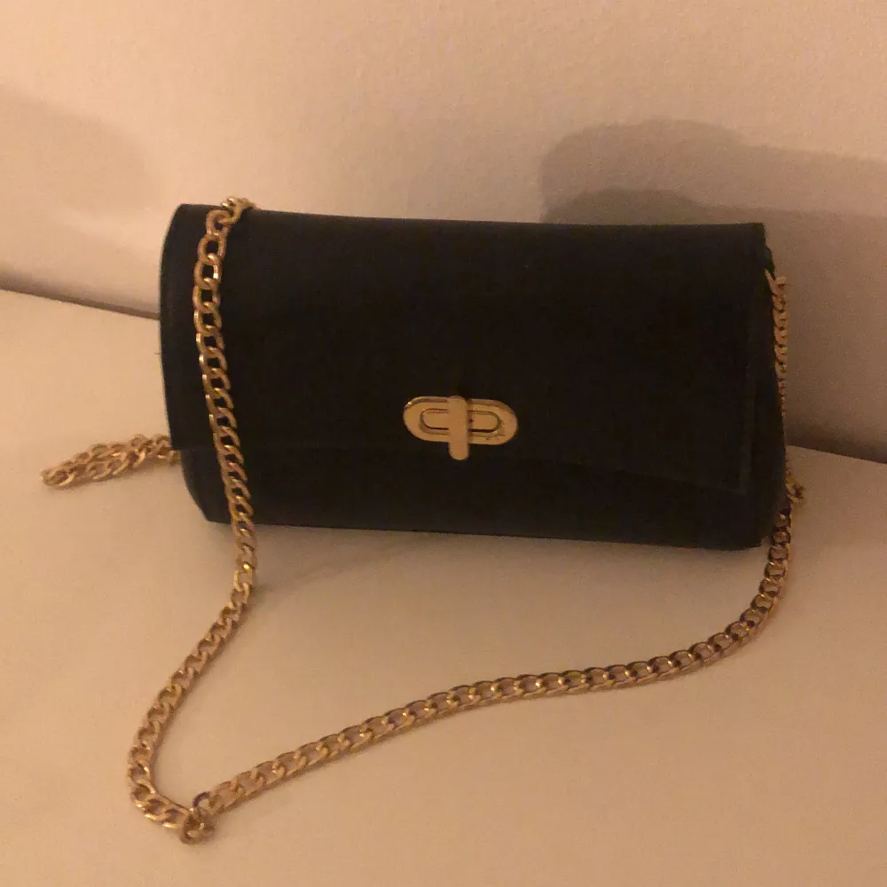 En liten svart handväska med guldigt kedjeband. Aldrig använd. Väskor.