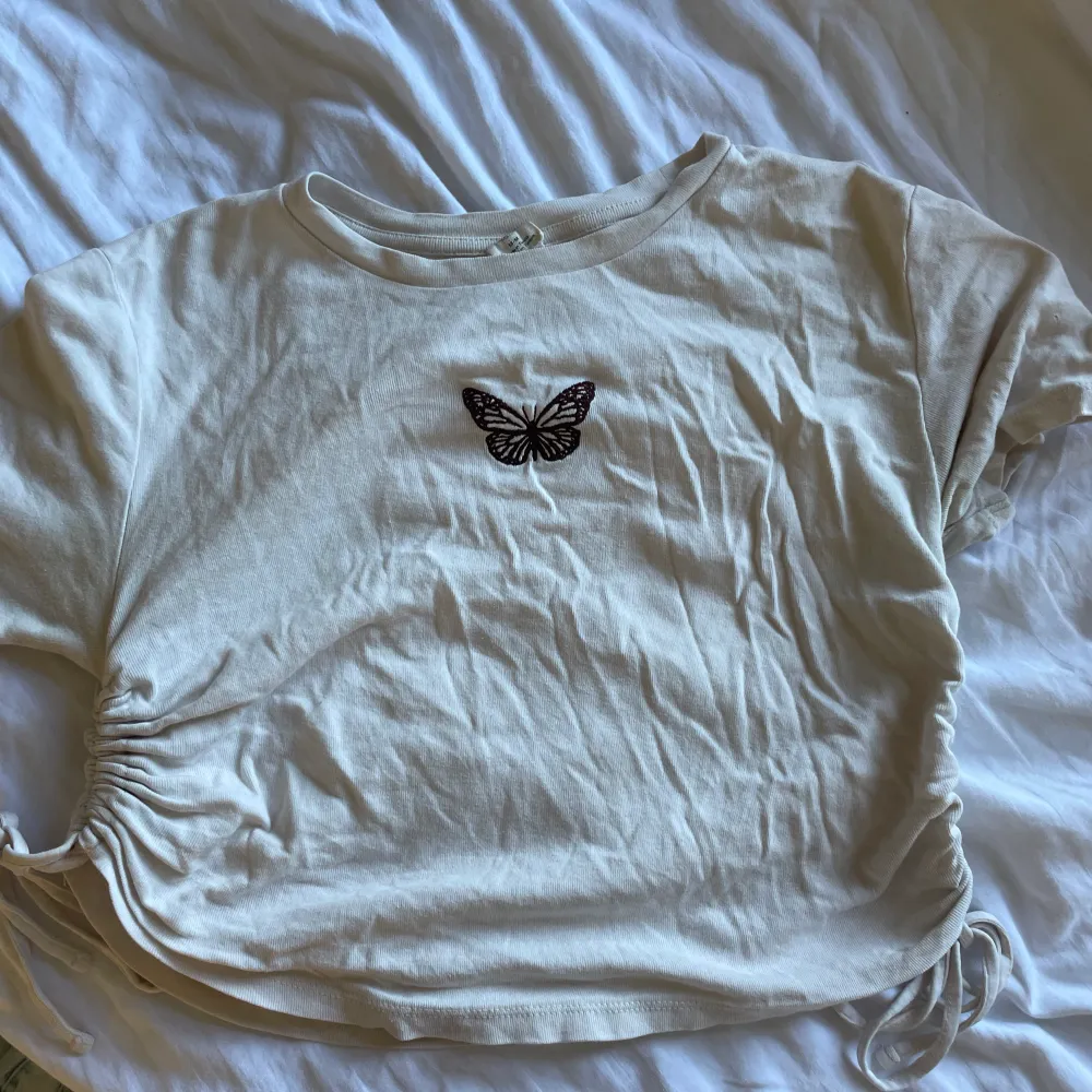 Supersöt och mjuk t-shirt från Urban outfitters med justerbara ihopdragningar på sidorna och en broderad fjäril i mitten av tröjan. Storlek M men skulle säga att den egentligen är xs-s. T-shirts.