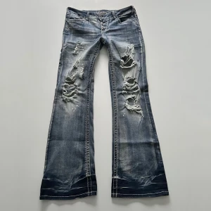 Lågmidjade jeans - Lågmidjade bootcut jeans med hål / slitningar från Rainbow. Midjemått: 80 cm, stretchiga. Innerbenslängd: 80 cm. Jag är 176 cm 💓