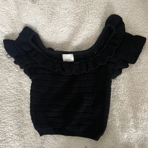 Svart stickad topp med volanger - En jättefin svart stickad topp från HM. Köpt i somras men är inte längre min stil.
