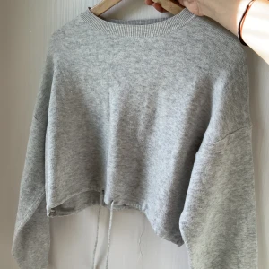 Cropped sweater - Grå kroppad sweater från Bershka i storlek S. Använd få gånger. Har ett snöre vid midjan så man kan knyta där🌟 perfekt till hösten och bra basplagg. 