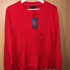 Stickat Tommy Hilfiger Red Knit Jumper  - Röd Tommy Hilfiger Kofta/ Jumper  Storlek M  Helt ny, oanvänd och prislappen sitter kvar. Skriv gärna vid övriga frågor