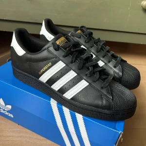 Adidas Superstar  - Helt nya svarta superstar, aldrig använda men kom med en liten skråma
