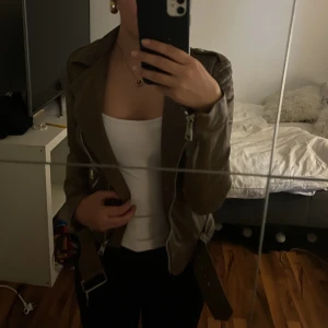 Brun vintage läder jacka - SVINSNYGG brun läderjacka med coola detaljer och bälte. Har varit en favorit men säljer nu då den är lite för liten❤️Enda defekten är att ena dragkedjan på ärmen är sönder, men de går fof och dra upp. Skriv ifall de är några frågor 💕