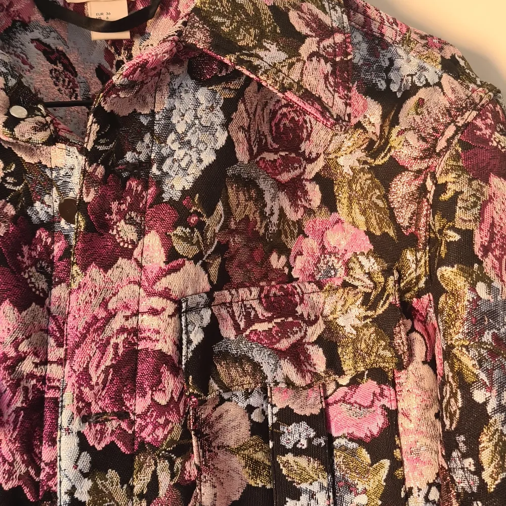 Supersnygg jacka med broderade blommor och glittrigt tyg. Oanvänd.. Takit.