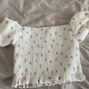 Somrig topp - En knappt använd vit topp med blommigt motiv. Strl M