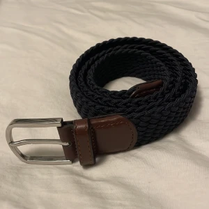 John Henric skärp - Snyggt, stilrent bälte från John Henric. Mörkblått med bruna detaljer. Perfekt skick. Storklek S, men flätat så det kan anpassas till vilken storlek som helst. Köptes för 500kr, säljs för 200kr. Priset kan diskuteras vid snabb affär, fråga gärna!