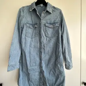 Denim dress with pockets and buttons. Reaches to mid-thigh. Loose fit. 