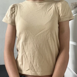 Beige tröja med kort puffärm - T-shorts med kort puffärm i färgen beige. Från lager 157 och använd vid endast några få tillfällen. Köparen står för frakt💕
