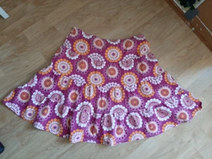 Kjol - Kjol av märket me&i. Rosa botten med mönster i vitt och orange.  95 % bomull, 5 % elastan. Öko-tex standard. Ca 50 cm lång. 