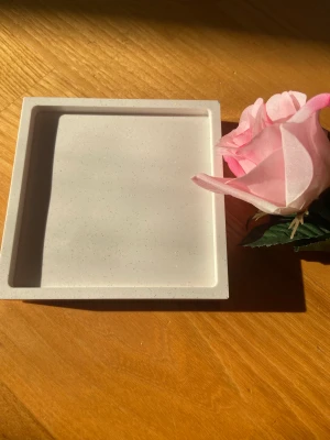 Dekorationsplatta  - Superfin platta som glittrar. Perfekt att ha som bakgrund till bilder på något, te.x. smycken. Från eget företag som inte finns längre, Jt form. Deras logga finns på baksidan. Det finns lite sprickor på kanterna och en liten på ett av hörnen. 