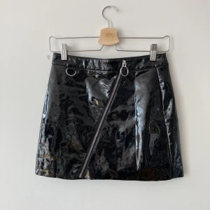 Kjol lack Junkyard - Supersnygg svart lackkjol från Junkyard med dragkedja fram. Aldrig använd så har bara legat i garderoben. 