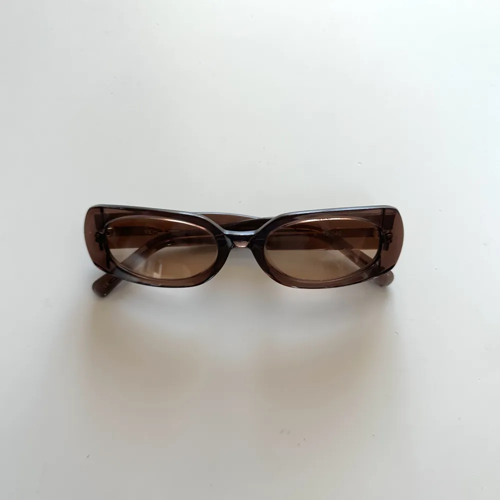 Solglasögon med brunt transparent glas. Små repor förekommer.. Accessoarer.