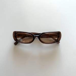 Solglasögon med brunt transparent glas. Små repor förekommer.