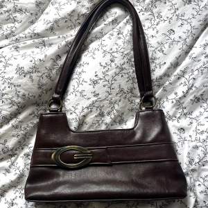 Säljer nu denna galet snygga vintage-handväskan!💘 Den är mörkbrun, har fyra fack som förseglad med blixtlås och har inga synliga defekter. Är inte helt säker på märket men tror att det är Gussaci i och med G-loggan i metall.