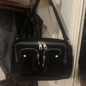 Nunoo svart väska - Liten väska från märket Nunoo i modellen ellie använd kanske två gånger så i perfekt skick! Perfekt nu till sommarn med en liten axelväska med fina detaljer🤞 en avtagbar och justerbar axelrem tillkommer!