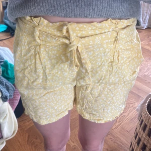 Gula somriga shorts - Ett par jätte fina gula shorts med vita blommor på. Är perfekt till sommaren. Storlek 140 men går att töja ut vid midjan.Vill inte ha dem längre.