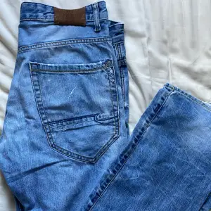 Slitna blå jeans med litet hål vid ena bakfickan, ganska små i storleken 