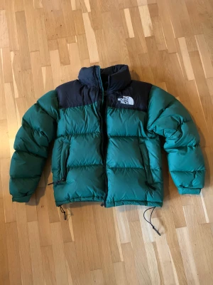 North Face Retro Nuptsee 1996 - Jackan har använts under en vinter och ena snöret som spänner fast jackan vid midjan har gått sönder (annars är jackan i nyskick). Den är i storlek S och passar folk som är 160-175cm lång. Hör av dig om du har någon fråga🤙 Priset kan sänkas vid snabbaffär