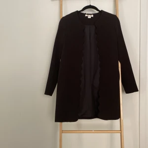 Lång svart kavaj st xs - Svart fin kappa eller kavaj utan knäppning.  Superfin med tun top under. Rak modell Hm st 32 men motsvarar mer 34 eller xs.  Fint skick, inga hål etc!  Säljes pga för liten