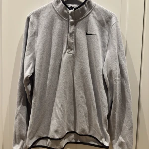 Nike halfzip - En grå nike halfzip i fleecetyg som är perfekt om man vill värma sig efter ett träningspass ute, säljer även en i svart, köpt för runt 800kr men jag säljer för endast 300, storlek M men passar även S