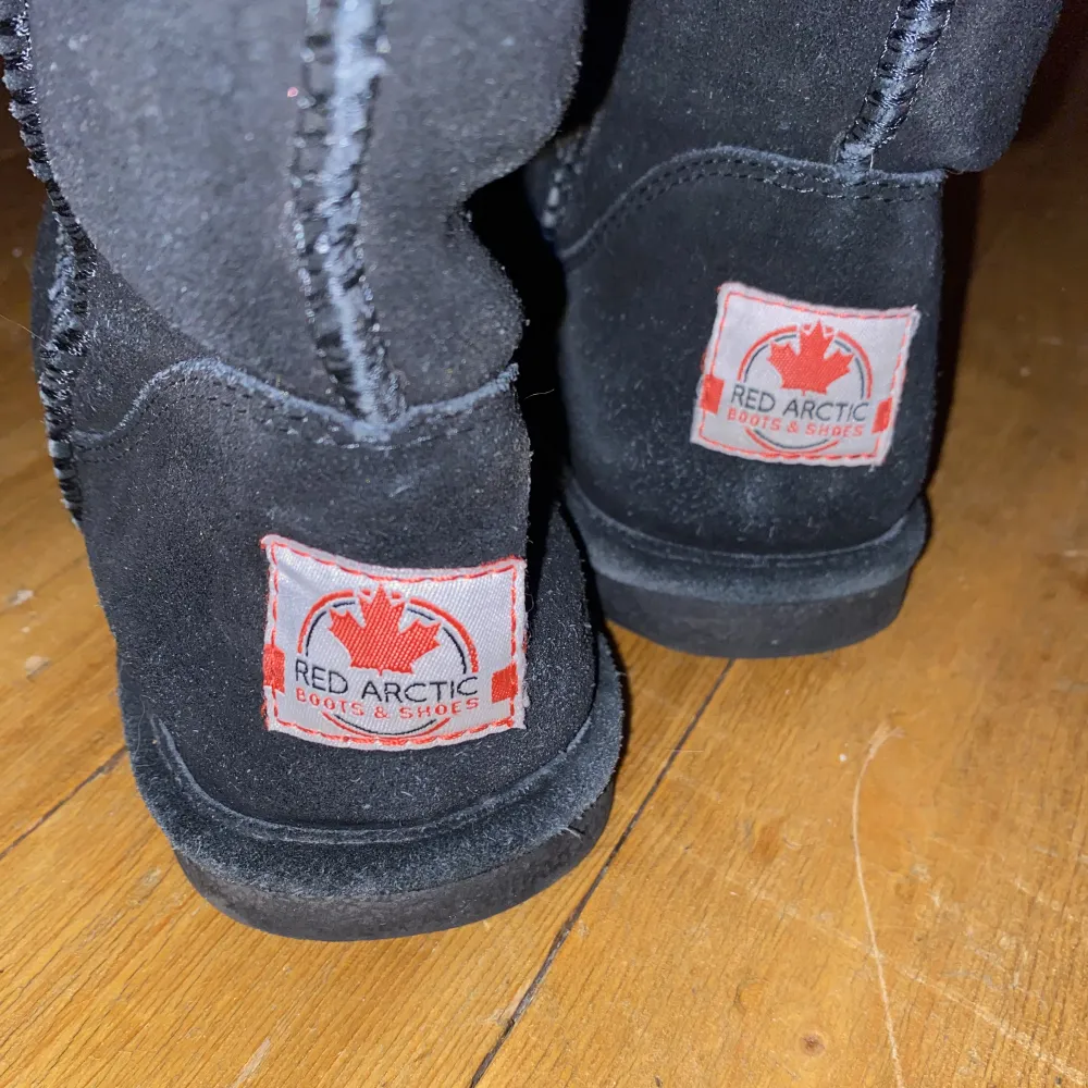 Höga svarta Uggs liknande vinterskor. Skorna är från märket Red arctic i storleken 39. Skorna är använda på vintern i blött väder och därav har materialet blivit lite nopprigt.. Skor.