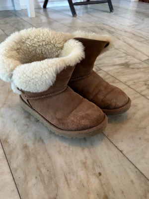 UGG Boots - Ett par bruna UGG boots med fina knappar på sidorna i storlek 33!💗💗💗 Pris: 300 kr