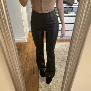 Utsvängda skinnbyxor - Långa utsvängda skinnbyxor. Liiite korta på mig som är 179 cm med jättelånga ben. Mocka på insidan så de är bekväma. Nyskick, använda en gång. 