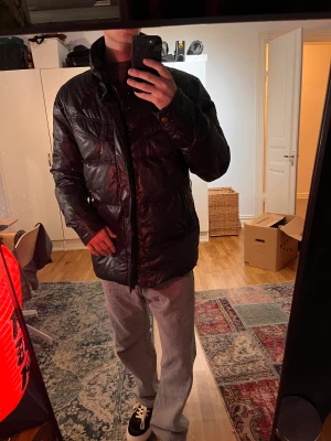 Dunjacka matchless  - Lyxig dunjacka från Matchless, noggrant tillverkad i Italien. Framställd i waxed cotton vilket ger den en särskild lyster och hållbarhet. Storlek Large. Med ett ursprungligt pris på 8000 kr, är detta en elegant kombination av stil och funktion.