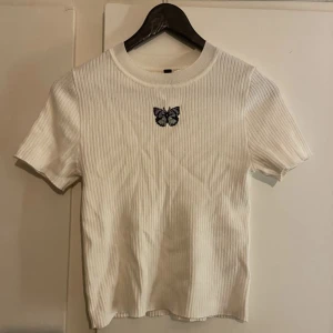 Vit t-shirt med fjäril  - Oanvänd vit t-shirt säljes då den inte riktigt passade mig från H&M. Frakt ingår ej. Storlek S 