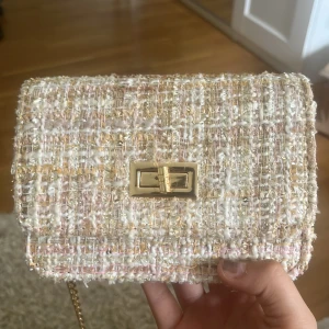 Handväska - Jättegullig liten handväska i tweed. Väskan är köpt på Jackie för ca 2 år sedan för 799 kr. Använd bara en gång så är i princip i nyskick. Väskan har en höjd på 11 cm och en bredd på 16 cm