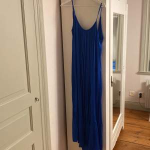 Lång klarblå klänning i tunnt/blankt material. Endast provad.  