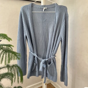 Stickad kofta - Blå stickad kofta från Nelly i storlek S. Använd 1 gång men fastnat i ett annat klädesplagg och gjort en liten reva på ett ryggen, syns mer på insidan än på utsidan. Annars i ett bra nytt skick.💙